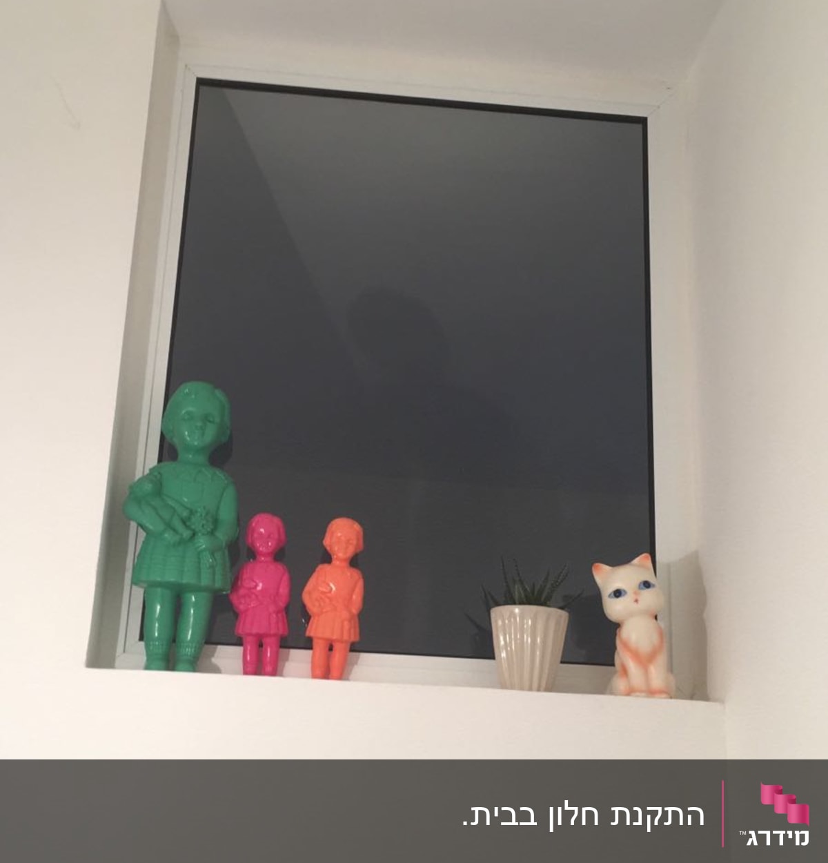 חלון אלומיניום עם פסלונים צבעוניים על אדן החלון